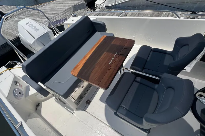 Chill Yacht Photos Pics Nimbus T8 2025 boat interior with seating and wooden table, dockside view.
