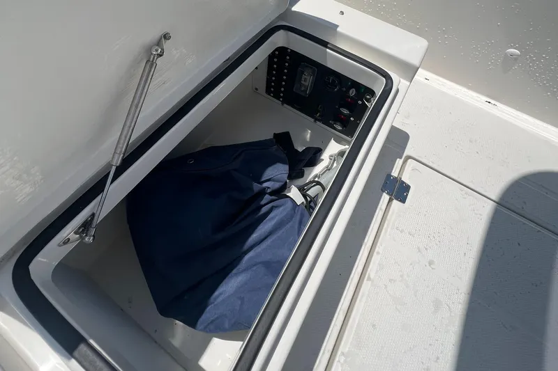 Chill Yacht Photos Pics Storage compartment in a 2025 Nimbus T8 boat, featuring a blue bag and control panel.