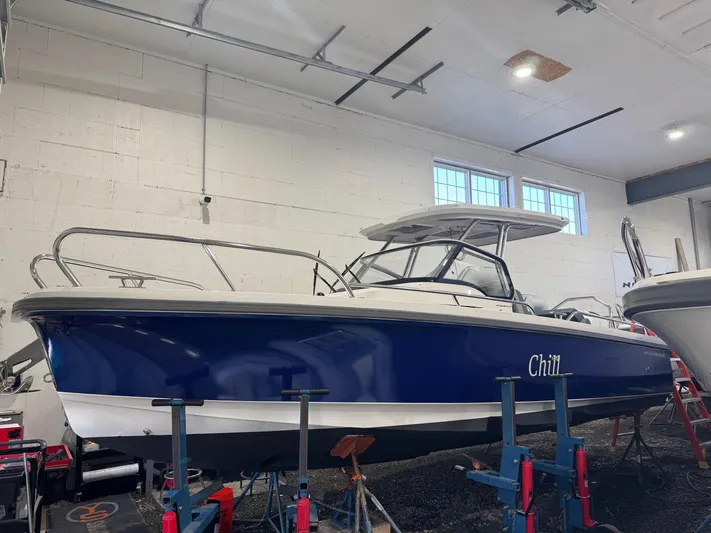 Chill Yacht Photos Pics 2025 Nimbus T8 boat in a garage, blue hull, elevated on stands.