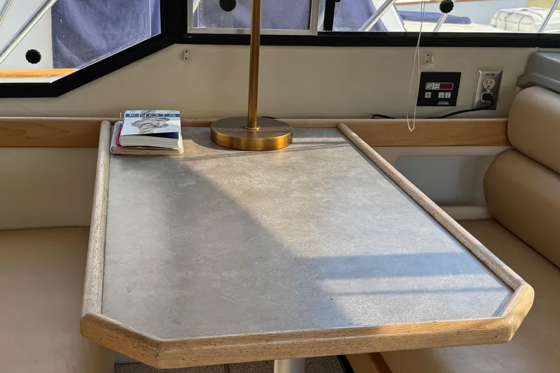 Interim Yacht Photos Pics Interior of 2001 Bayliner 4087 yacht with table, lamp, and book by window.