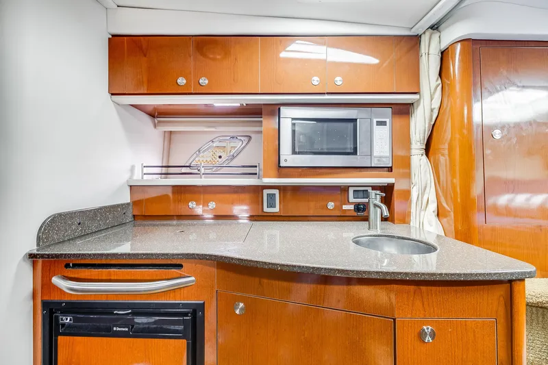  Yacht Photos Pics 2014 Sea Ray 330 Sundancer galley with microwave, sink, and wooden cabinetry.