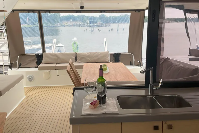  Yacht Photos Pics Interior view of 2017 Fountaine Pajot Lucia 40 catamaran with dining area and scenic water backdrop.