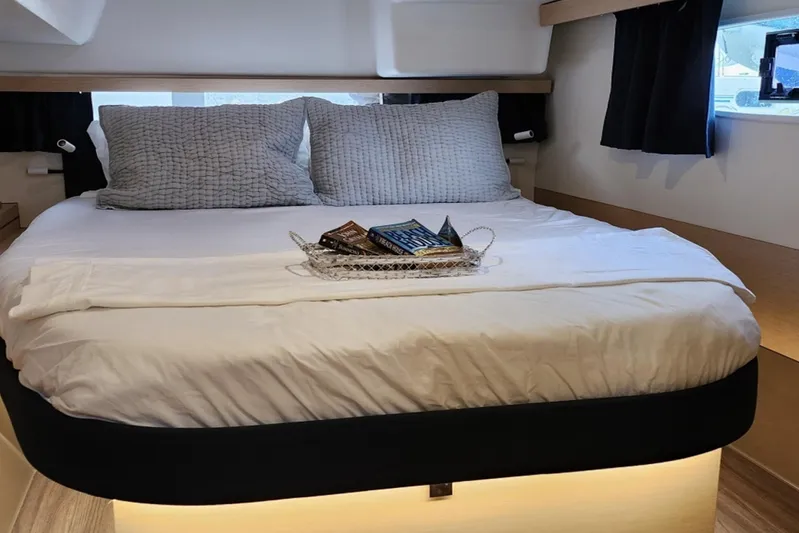  Yacht Photos Pics Cozy bedroom in 2017 Fountaine Pajot Lucia 40 catamaran with plush bedding and reading materials.