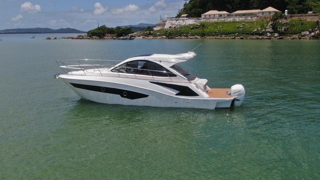 2023 Evolve 400HT yacht on calm water near a scenic shoreline.