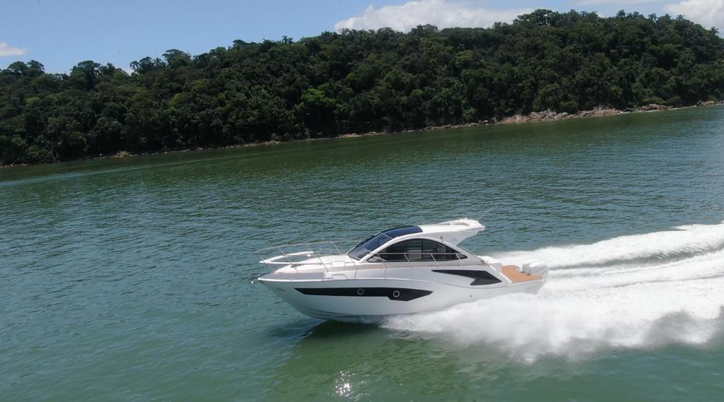 2023 Evolve 400HT yacht cruising on a scenic lake with lush green forest backdrop.