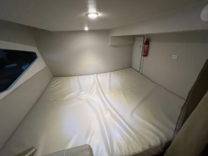 Elena Yacht Photos Pics 2023 Evolve 400HT cabin interior with bed, window, and fire extinguisher.