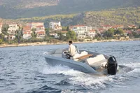 Modern Rand Source 22 boat cruising near coastal town, 2023 model.