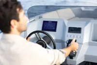 Man steering Rand Source 22 boat, 2023 model, with modern dashboard controls.
