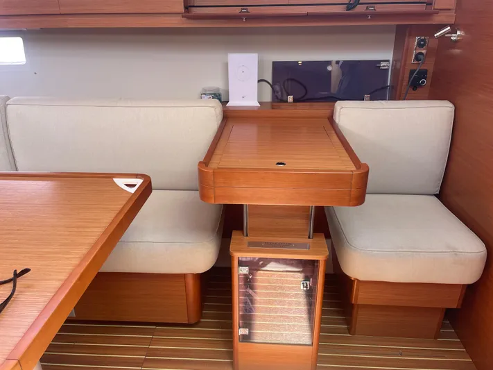 Send Me Yacht Photos Pics Interior of 2018 Dufour 460 Grand Large yacht with wooden table and cushioned seating.