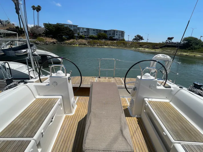Send Me Yacht Photos Pics Dufour 460 Grand Large 2018 yacht deck with dual steering wheels and scenic waterfront view.