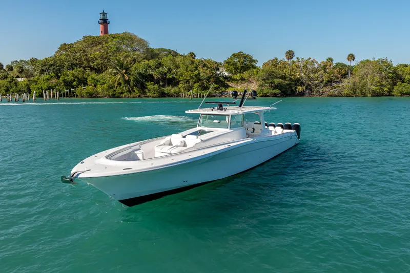  Yacht Photos Pics 2026 HCB 65 Estrella boat on clear water near a lush, green shoreline with a lighthouse.