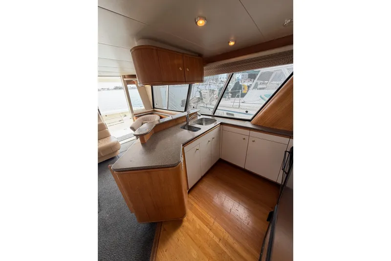 B Liner Yacht Photos Pics 1998 Bayliner 4788 Pilot House Motoryacht kitchen with wood cabinets and large windows.