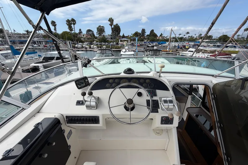 B Liner Yacht Photos Pics 1998 Bayliner 4788 Pilot House Motoryacht helm with marina view, featuring steering wheel and controls.