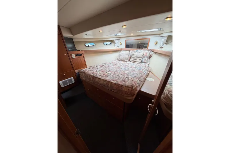 B Liner Yacht Photos Pics Cozy bedroom in 1998 Bayliner 4788 Pilot House Motoryacht with wood accents and porthole windows.