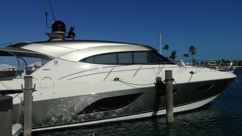 Chapter II Yacht Photos Pics 2023 Riviera 6000 Sport Yacht docked in sunny marina, sleek design, clear blue sky.