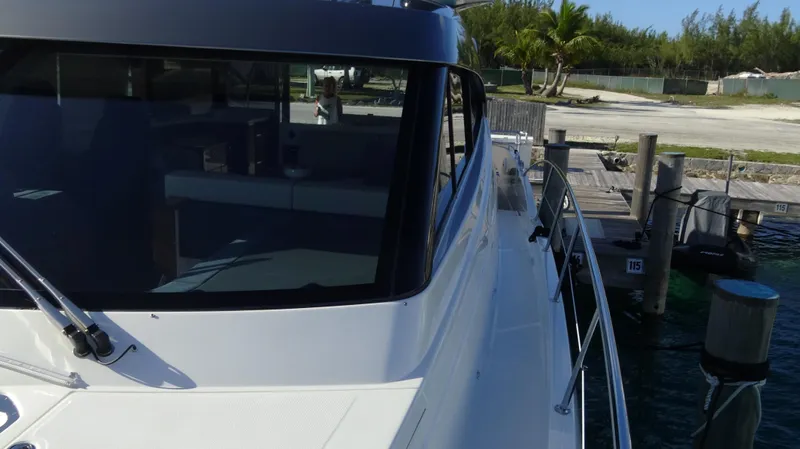 Chapter II Yacht Photos Pics 2023 Riviera 6000 Sport Yacht docked by a tropical shoreline.