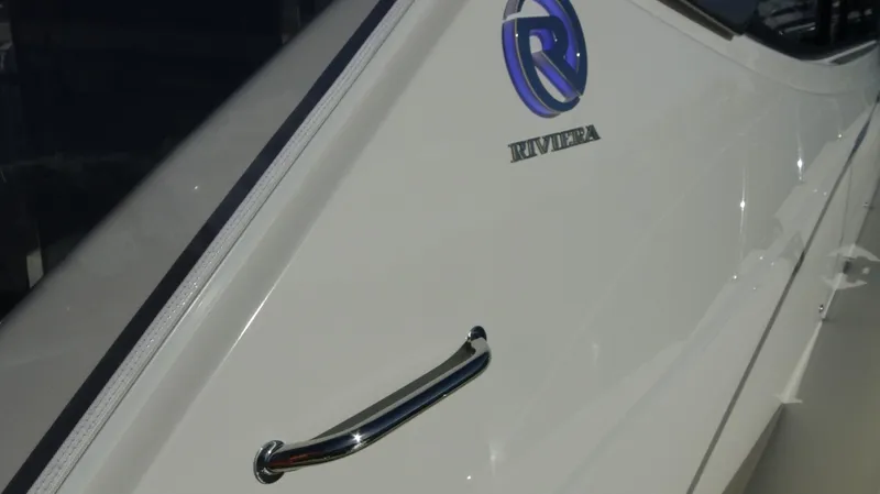 Chapter II Yacht Photos Pics 2023 Riviera 6000 Sport Yacht, sleek white exterior with logo and chrome handle.