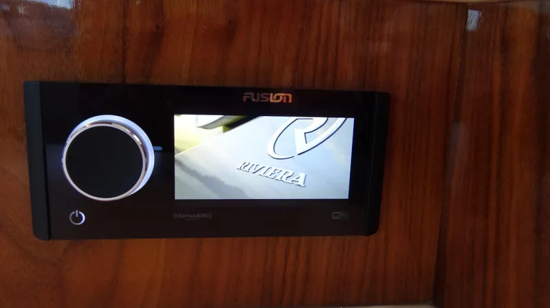 Chapter II Yacht Photos Pics Fusion stereo system on 2023 Riviera 6000 Sport Yacht, wood panel background.