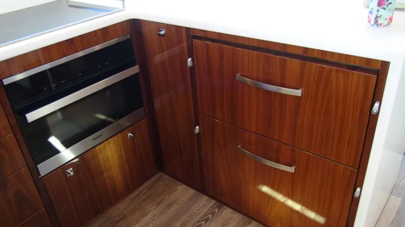 Chapter II Yacht Photos Pics 2023 Riviera 6000 Sport Yacht kitchen with wood cabinetry and modern appliances.