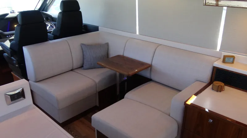 Chapter II Yacht Photos Pics 2023 Riviera 6000 Sport Yacht interior with plush seating and wooden table.