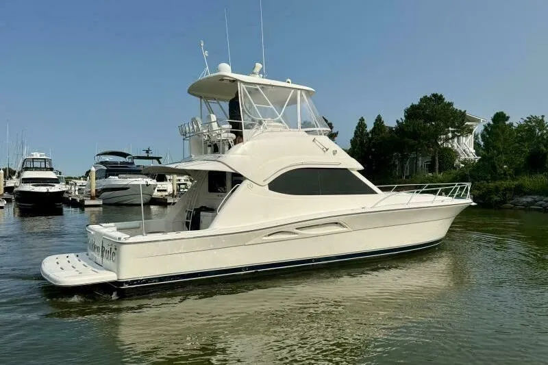 Golden Rule Yacht Photos Pics 2006 Riviera 42 Flybridge yacht docked in a serene marina setting.