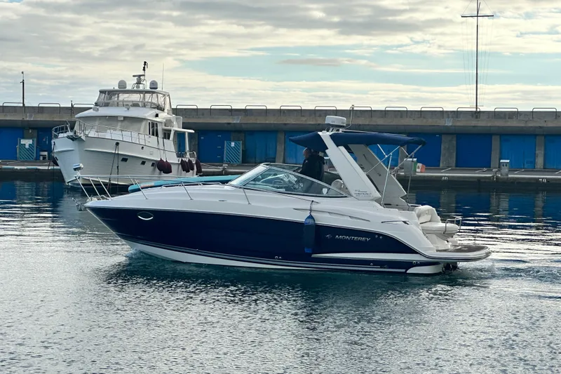 Key West Yacht Photos Pics 2011 Monterey 315 SCR boat cruising in a marina with a docked yacht nearby.