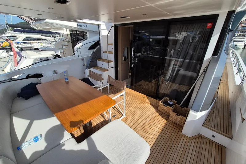  Yacht Photos Pics Luxurious 2023 Azimut Fly 68 yacht deck with seating and table, docked at marina.