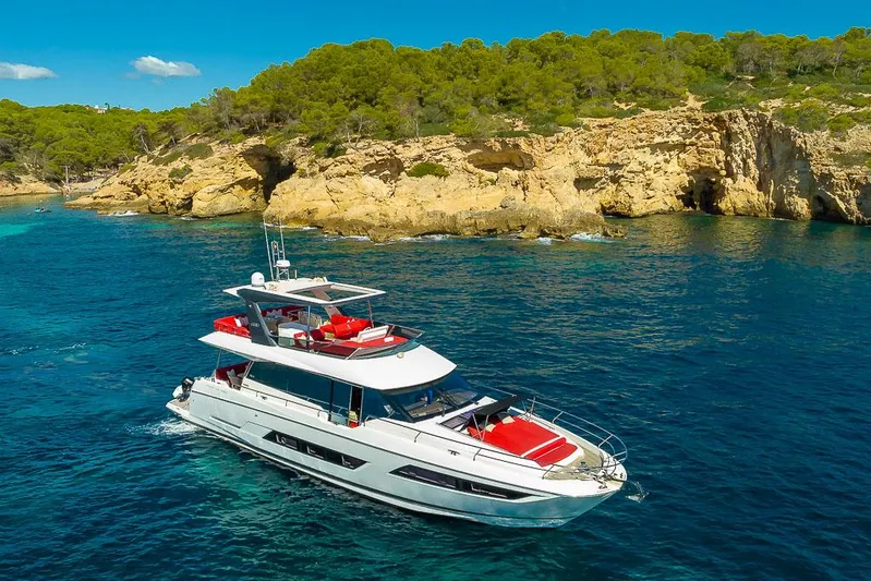  Yacht Photos Pics Luxury 2017 Prestige 680 yacht cruising near rocky coastline with lush greenery.