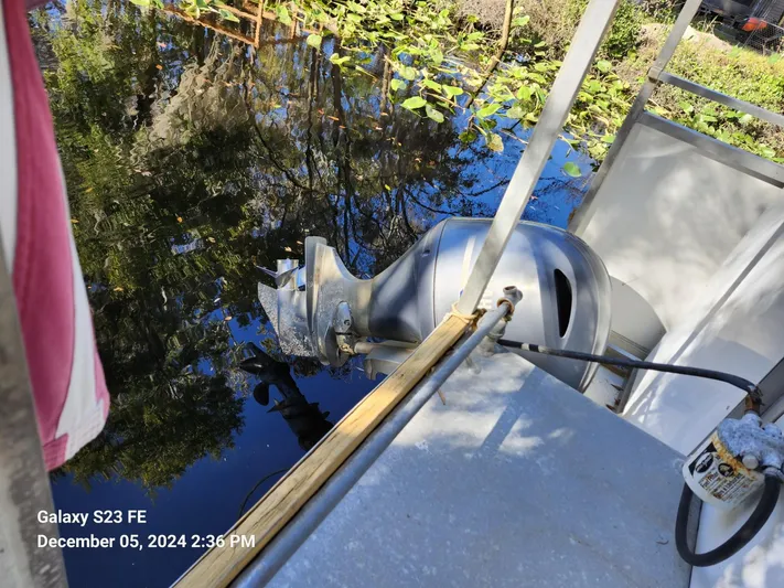 Sweet Tea Yacht Photos Pics Boat motor on a 2016 Rover Marine Carolina Rover 40, docked by a leafy waterway.