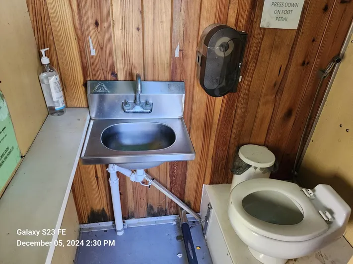 Sweet Tea Yacht Photos Pics Small bathroom with stainless steel sink, toilet, and wooden walls on a 2016 Rover Marine Carolina Rover 40.