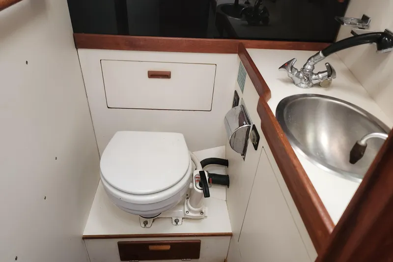 Isola Bella Yacht Photos Pics 1988 Sabre 42 yacht bathroom with toilet, sink, and wooden accents.