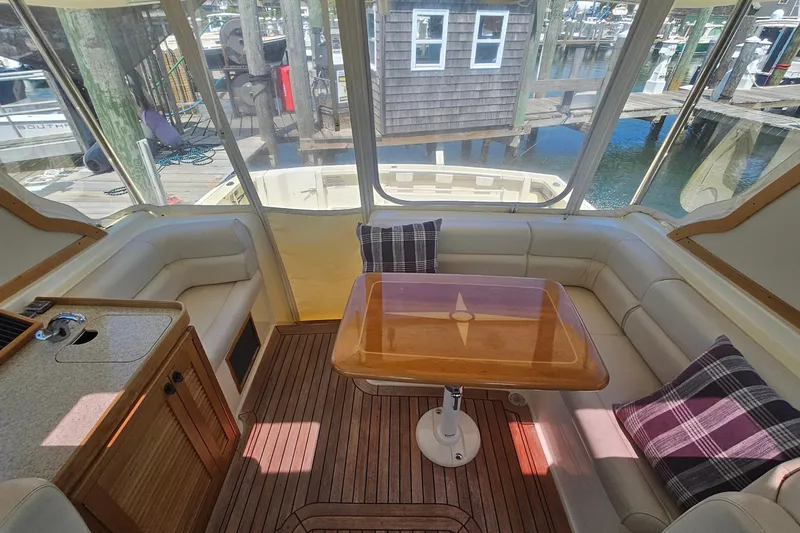  Yacht Photos Pics 2009 Sabre 42 Express yacht interior with wooden table, cushioned seating, and plaid pillows.