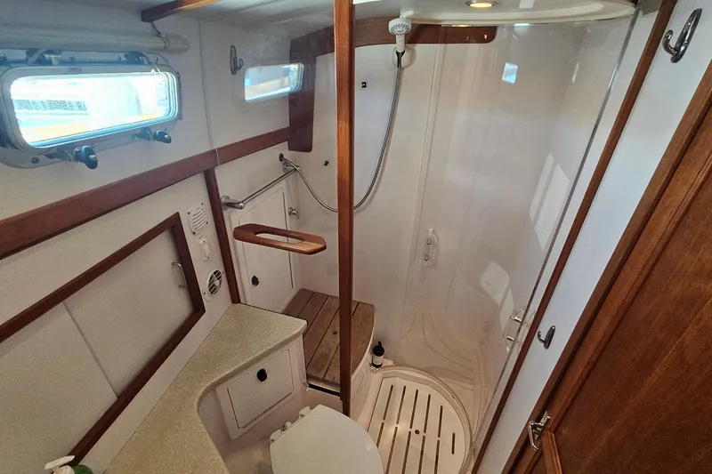  Yacht Photos Pics 2009 Sabre 42 Express yacht bathroom with shower, wooden accents, and porthole windows.