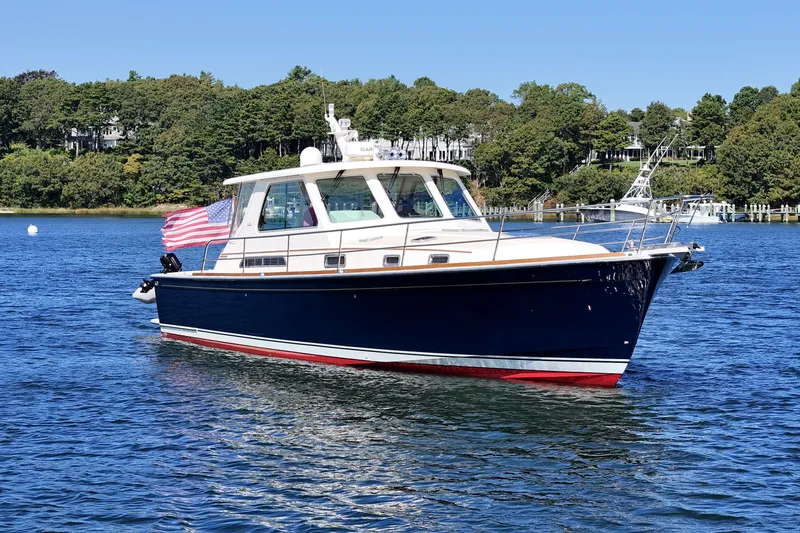  Yacht Photos Pics 2009 Sabre 42 Express yacht on calm water with American flag, surrounded by lush greenery.