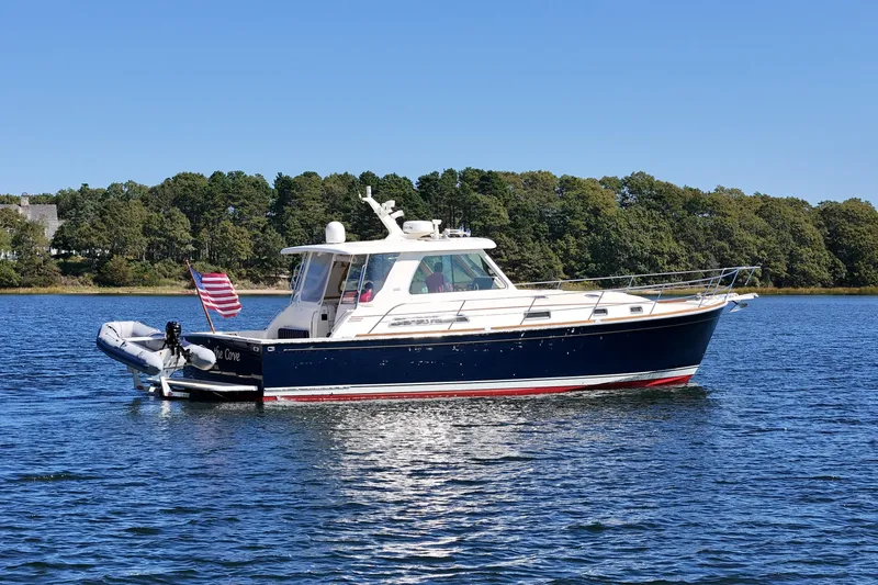  Yacht Photos Pics 2009 Sabre 42 Express yacht on calm water with American flag, surrounded by trees.