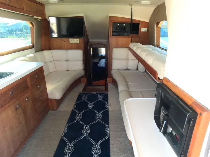  Yacht Photos Pics 2002 Luhrs 34 Convertible yacht interior with white seating, wood cabinetry, and mounted TV.