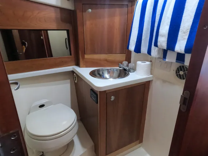  Yacht Photos Pics 2002 Luhrs 34 Convertible boat bathroom with sink, toilet, and striped towel.