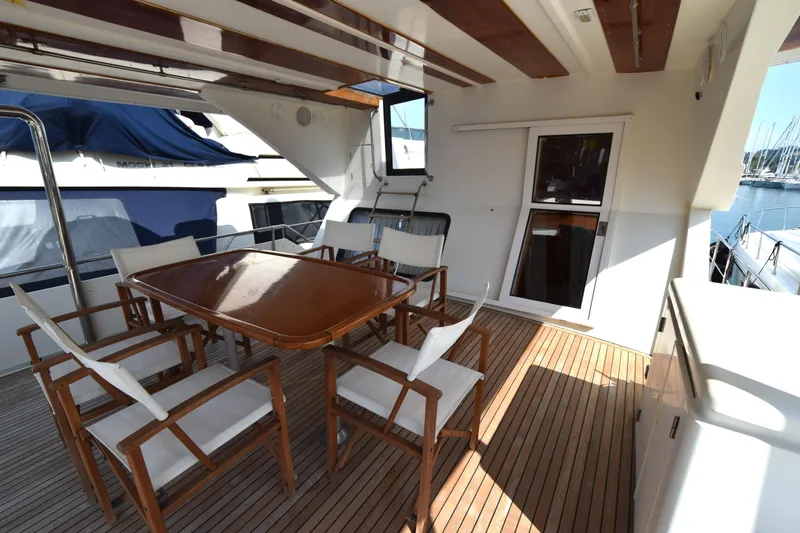 Odyssey Yacht Photos Pics Spacious deck area on 2000 Trader Sunliner 625 yacht with wooden table and chairs.