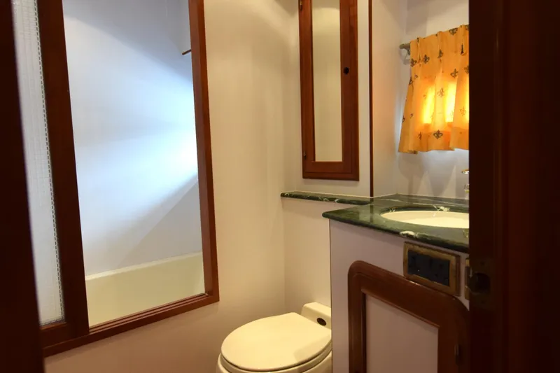 Odyssey Yacht Photos Pics Bathroom interior of 2000 Trader Sunliner 625 yacht with wooden accents and yellow curtains.