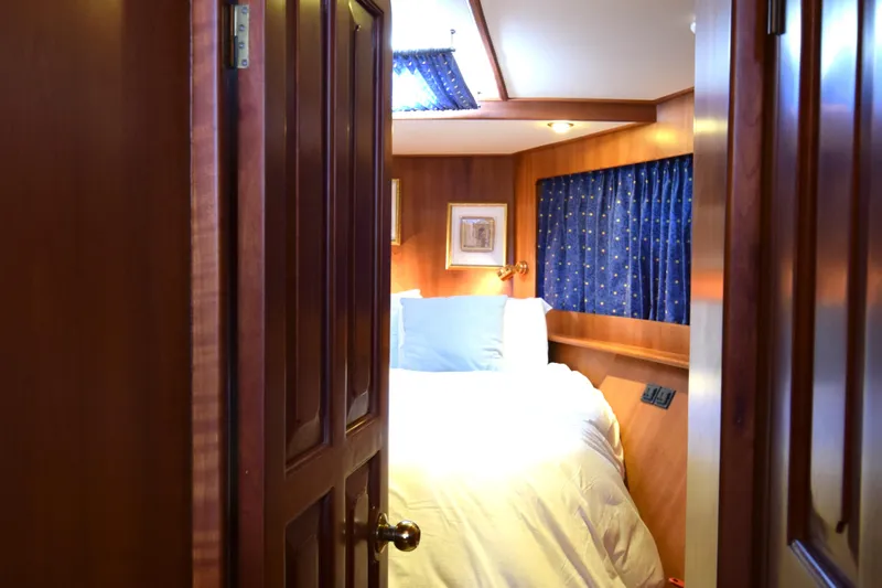 Odyssey Yacht Photos Pics Cozy bedroom interior on 2000 Trader Sunliner 625 yacht with wooden paneling and blue curtains.