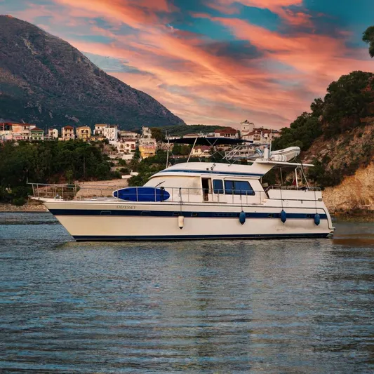Odyssey Yacht Photos Pics Trader Sunliner 625 yacht from 2000, docked near a scenic coastal village at sunset.
