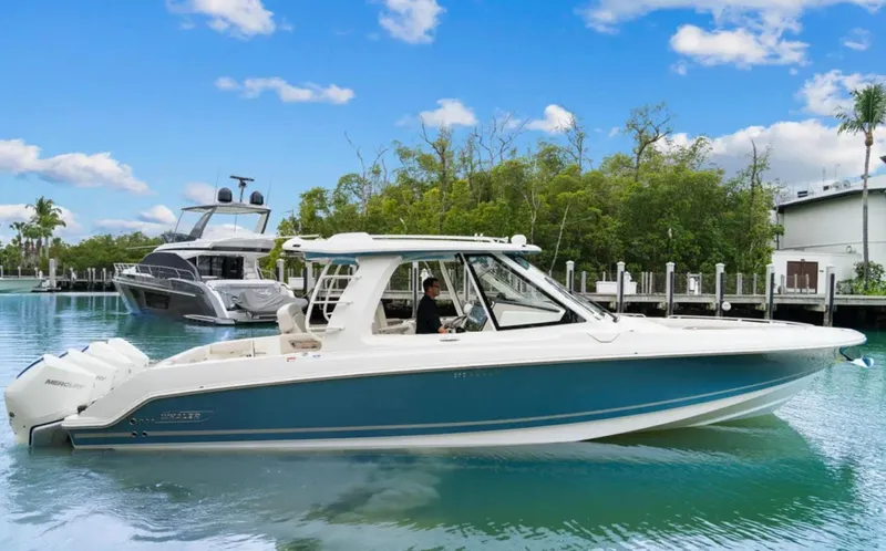 Hightide Yacht Photos Pics 2022 Boston Whaler 380 Realm boat on calm water, clear sky, and lush greenery background.