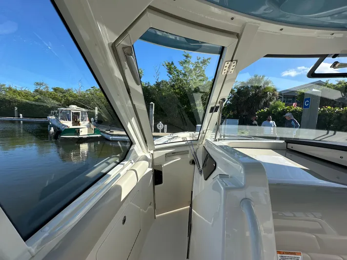 Hightide Yacht Photos Pics Interior view of 2022 Boston Whaler 380 Realm boat docked near lush greenery.