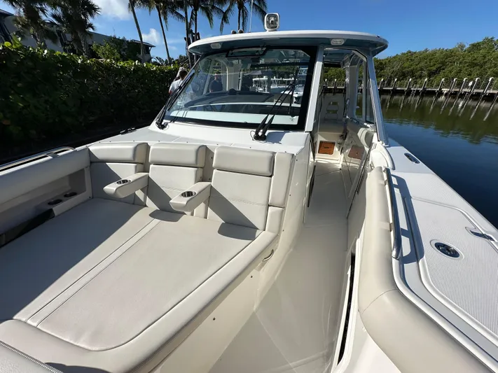 Hightide Yacht Photos Pics 2022 Boston Whaler 380 Realm boat interior with seating and console, docked by lush greenery.