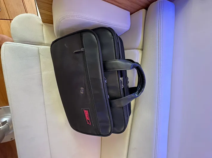 Hightide Yacht Photos Pics Black briefcase on a white cushioned seat inside a 2022 Boston Whaler 380 Realm.