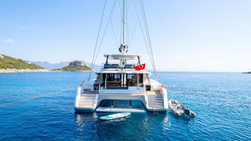  Yacht Photos Pics 2023 Fountaine Pajot Catamaran Alegria 67 anchored in serene blue waters.