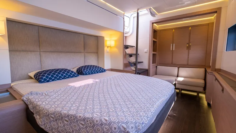  Yacht Photos Pics Luxurious bedroom in 2023 Fountaine Pajot Catamaran Alegria 67 with modern decor and cozy lighting.