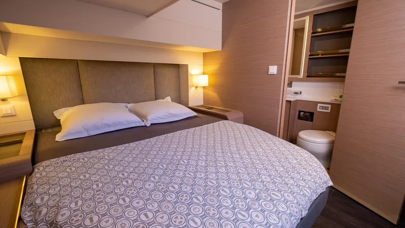  Yacht Photos Pics Luxurious bedroom interior of 2023 Fountaine Pajot Catamaran Alegria 67 with ensuite bathroom.