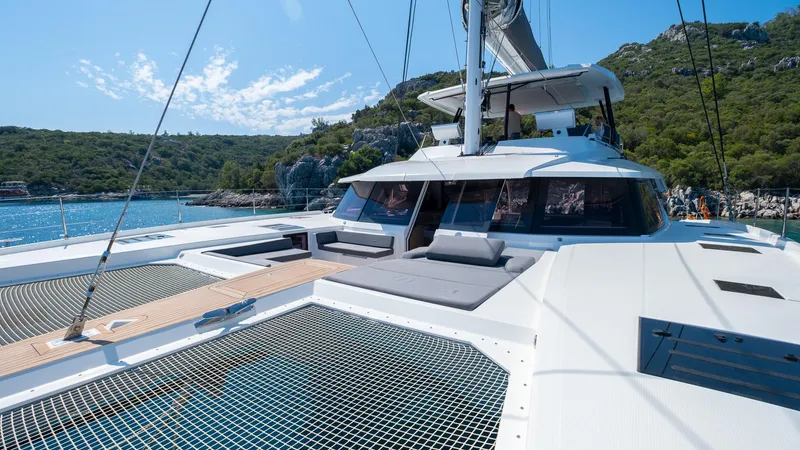  Yacht Photos Pics 2023 Fountaine Pajot Catamaran Alegria 67 on scenic water with lush hills.