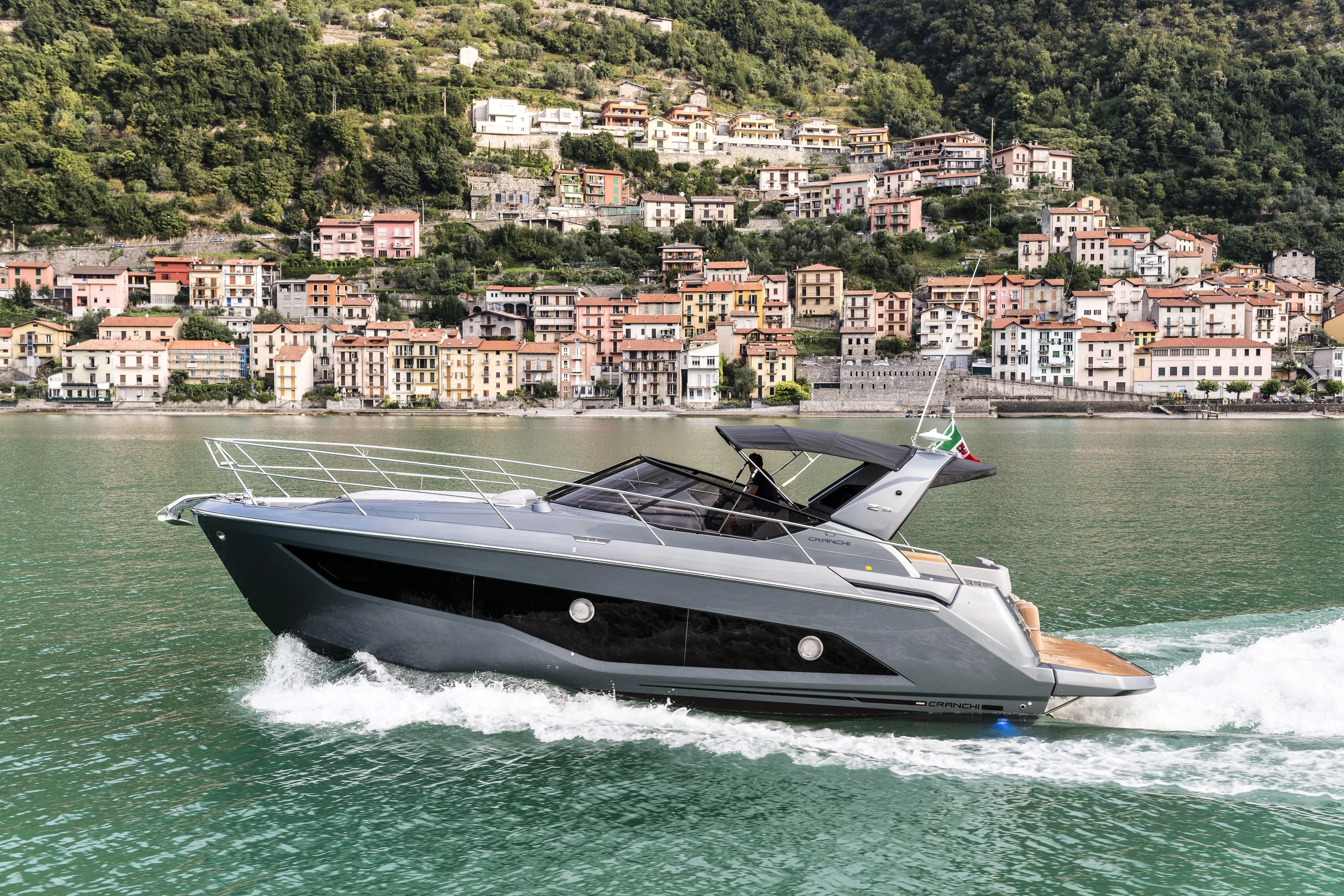  Yacht Photos Pics 2025 Cranchi Z35 yacht cruising on a scenic lake with hillside village backdrop.